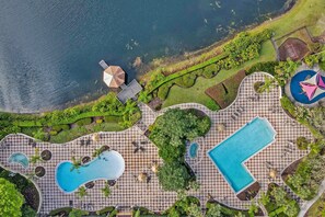 An aerial view of a resort with multiple swimming pools, a large central pool, and a beach area. - Spacious Townhouse With Themed Rooms and Resort Amenites (Davenport)