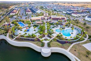 An aerial view of a residential area with a swimming pool, a bridge, and a park. - Spacious Resort Style Home w/ Enclosed Pool, Shared Pool & hot Tub,-dog Friendly (Kissimmee)
