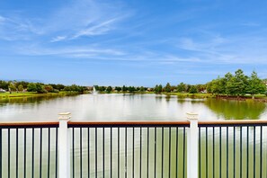 A calm lake with a fountain, surrounded by greenery and a clear sky. - Spacious Resort Style Home w/ Enclosed Pool, Shared Pool & hot Tub,-dog Friendly (Kissimmee)