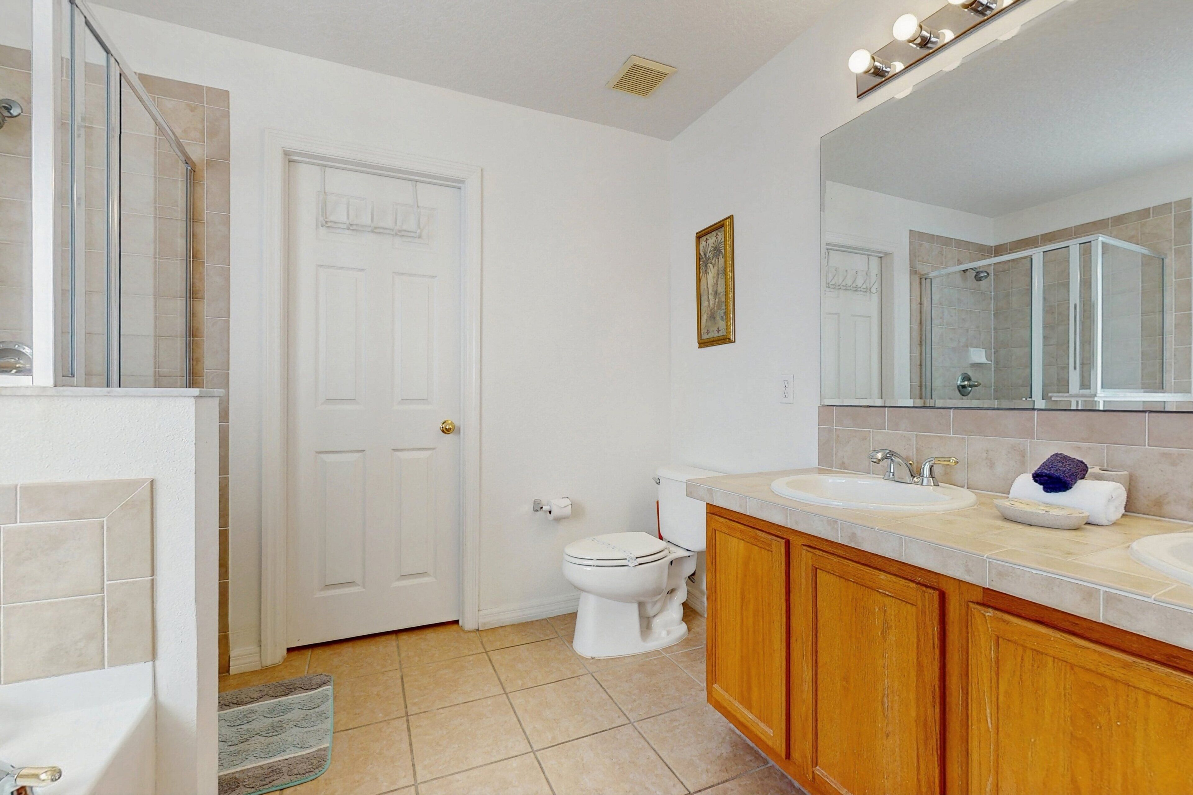 A bathroom with a bathtub, two sinks, a toilet, and a shower area.