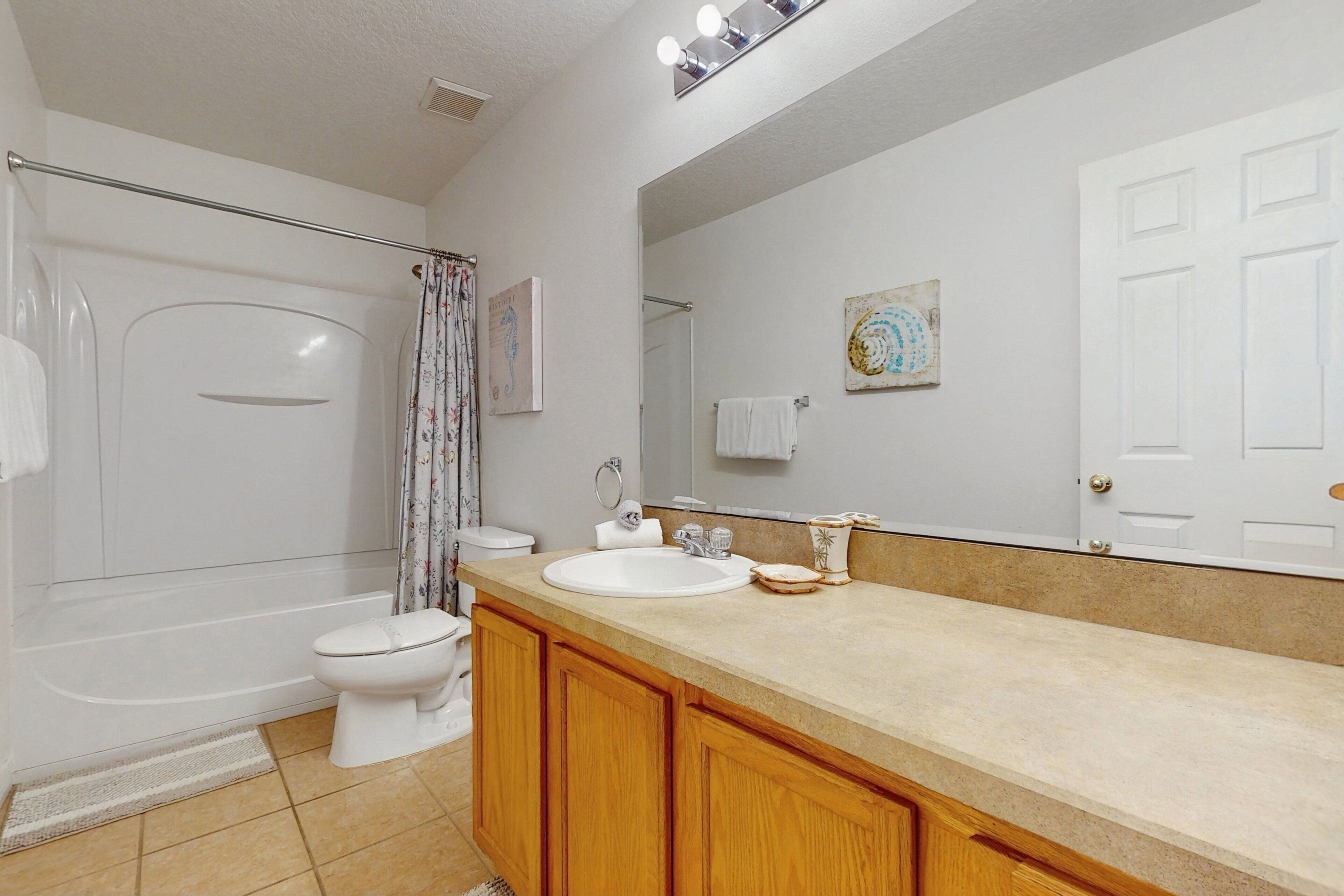 Une salle de bain avec une baignoire, des toilettes, un lavabo et un grand miroir.