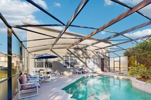 A covered outdoor swimming pool with lounge chairs and umbrellas, surrounded by a metal framework. - Gorgeous Private Home, Dog-friendly, Private Pool & Close to Parks (Davenport)