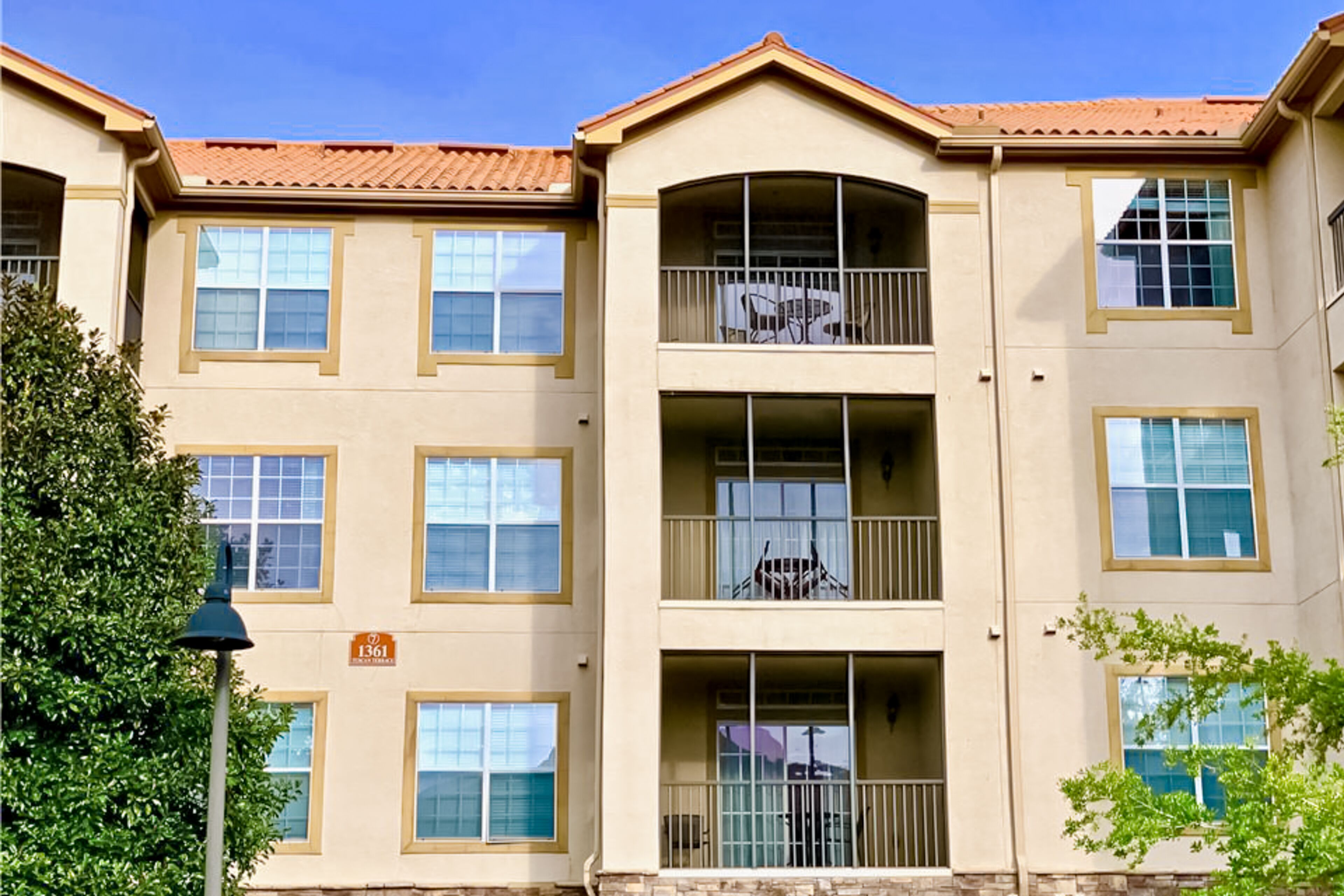 A multi-story building with balconies, a clear sky, and a street lamp.