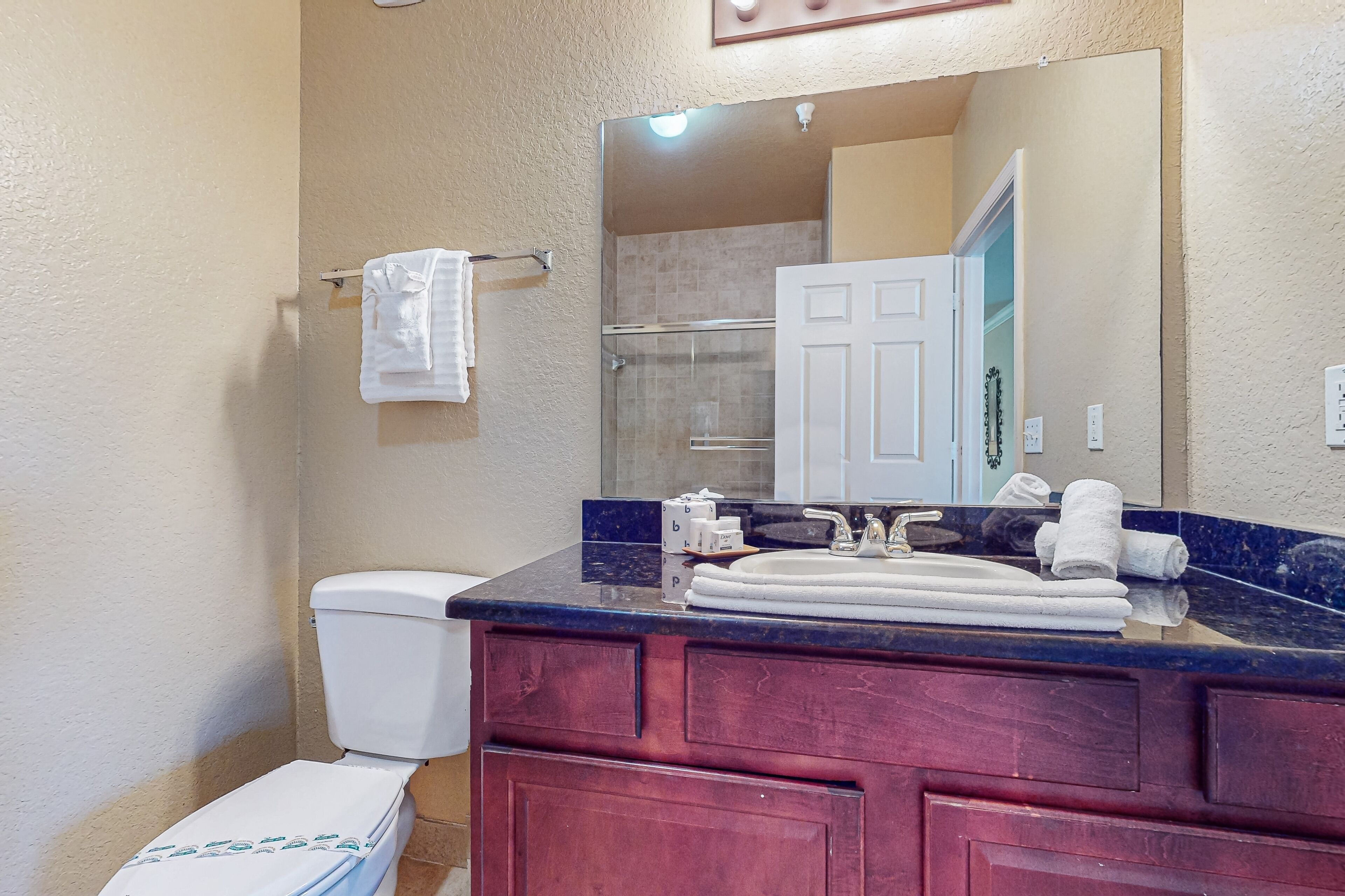 A bathroom with a white toilet, a sink with a mirror above it, and a shower area visible through a glass door.