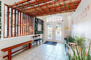 A restaurant interior with a wooden pergola, seating area, and a sign for 'VINEYARDS BAR & GRILLE'.