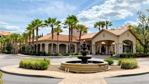 A hotel with a fountain in the courtyard, palm trees, and a tiled roof. - Resort Condo Close to Theme Parks With On-site Pool, Bar, Restaurant, & gym (Davenport)