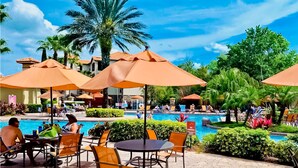 A poolside area with umbrellas, chairs, and a swimming pool. - Resort Condo Close to Theme Parks With On-site Pool, Bar, Restaurant, & gym (Davenport)