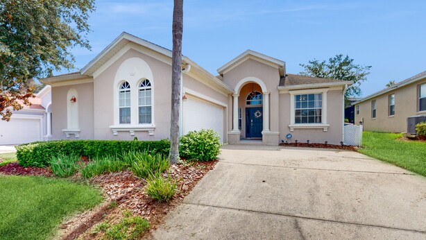 A two-story house with a front entrance, a garage, and a well-maintained lawn. - Single-story Home With Private Pool, Wifi, Central AC, WD and Full Kitchen (Haines City)