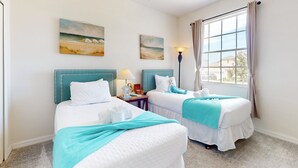 A hotel room with two beds, a ceiling fan, artwork on the walls, a lamp, and a window with curtains. - Single-story Home With Private Pool, Wifi, Central AC, WD and Full Kitchen (Haines City)