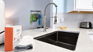 A modern kitchen with a stainless steel sink, white cabinets, and a 'Welcome' sign on the wall. - Single-story Home With Private Pool, Wifi, Central AC, WD and Full Kitchen (Haines City)