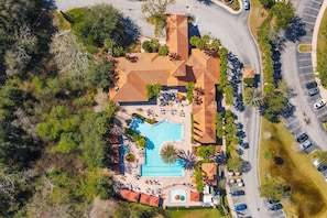 Vue aérienne d’un complexe hôtelier comprenant une piscine, plusieurs bâtiments et un parking.