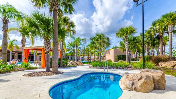 A swimming pool surrounded by palm trees and a covered seating area. - Solterra Escape Private Pool Café, Tennis & Water Park With Lazy River (Davenport)