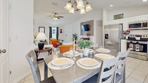 A modern kitchen with stainless steel appliances, a dining area with a table set for four, and a living room with a sofa and a television. - Dog-friendly, Private Pool , Central AC, Full Kitchen, Wifi, Snow-bird Friendly (Davenport)