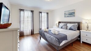 A bedroom with a bed, bedside tables, curtains, a painting, and a television. - Dog-friendly, Private Pool , Central AC, Full Kitchen, Wifi, Snow-bird Friendly (Davenport)