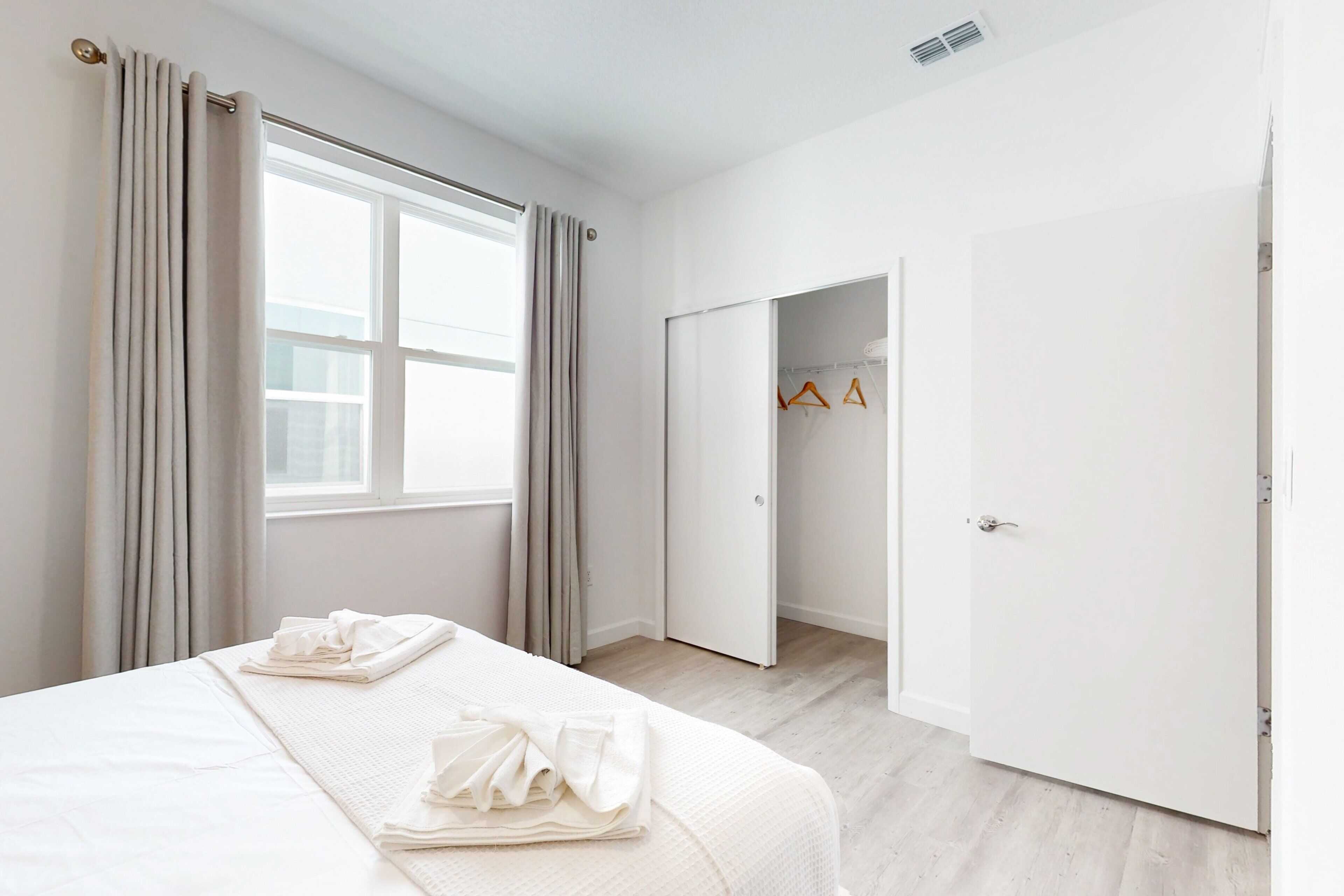 A hotel room with a bed, a wardrobe, and a door leading to a hallway.