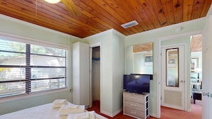 Quarto com cama, televisão, armário e porta de banheiro.