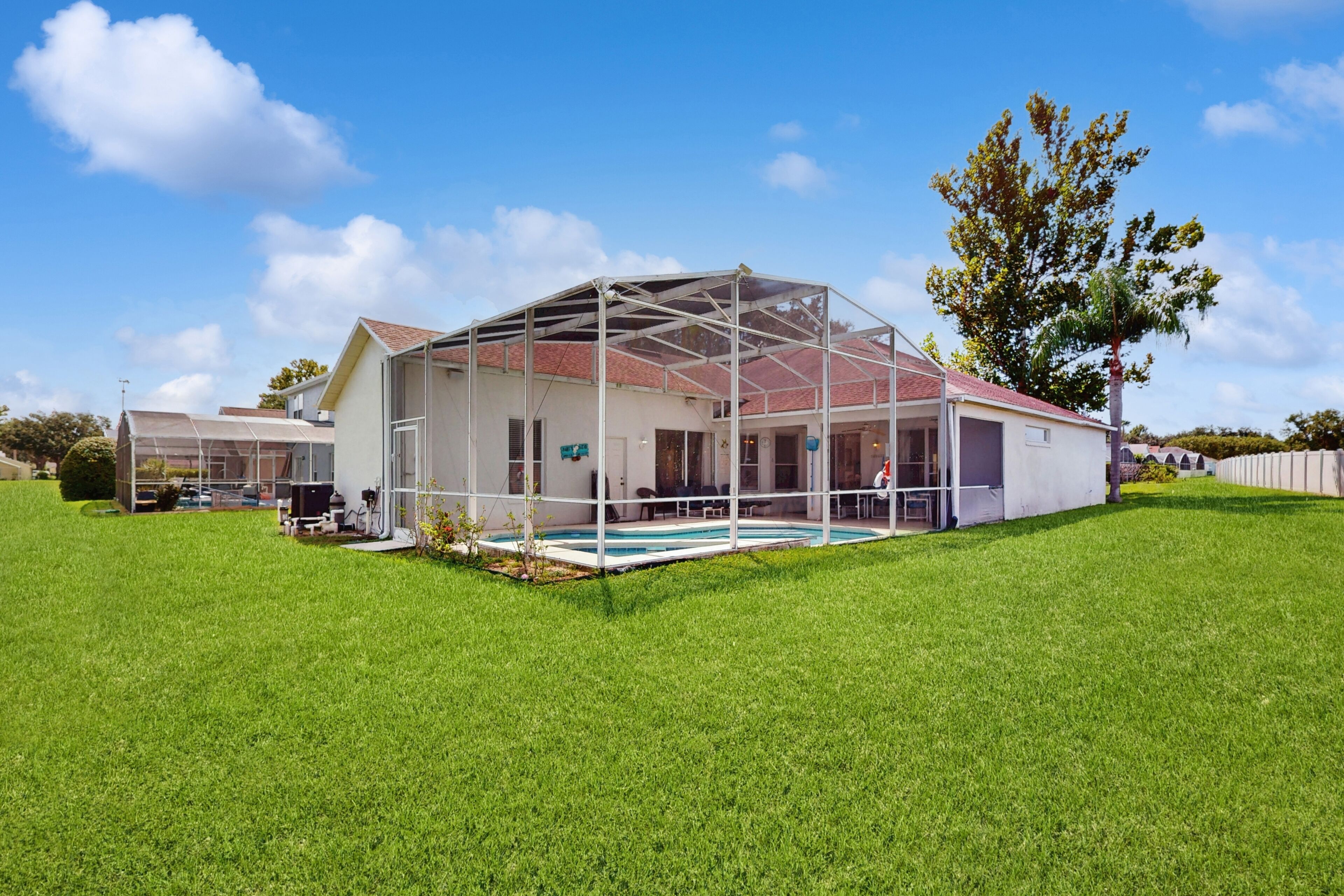 A house with a covered outdoor area, a swimming pool, and a lawn.