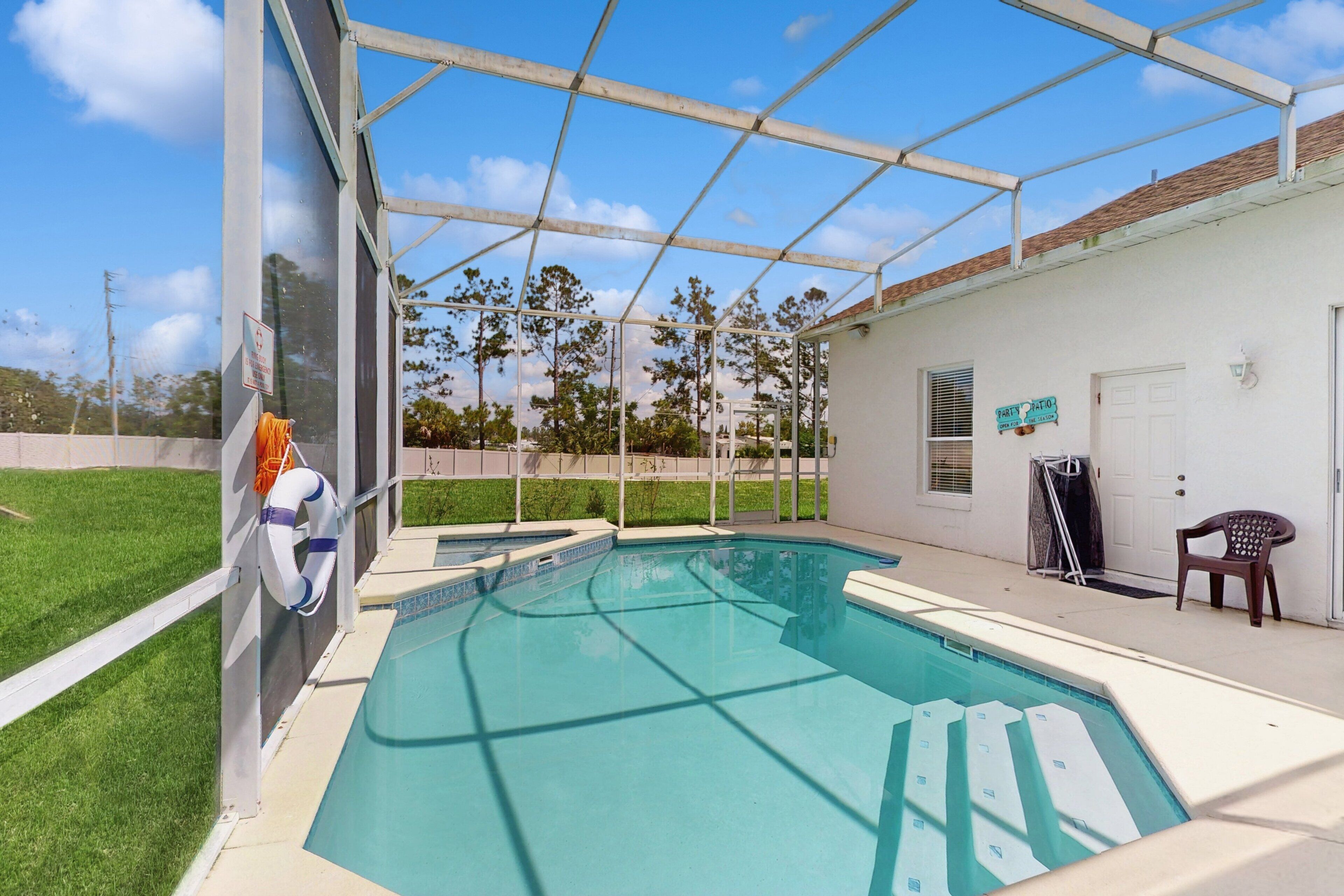 A swimming pool with a glass enclosure, a door, and a chair.