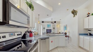 Une cuisine moderne dotée d’appareils électroménagers en acier inoxydable, de meubles blancs et d’un îlot central.