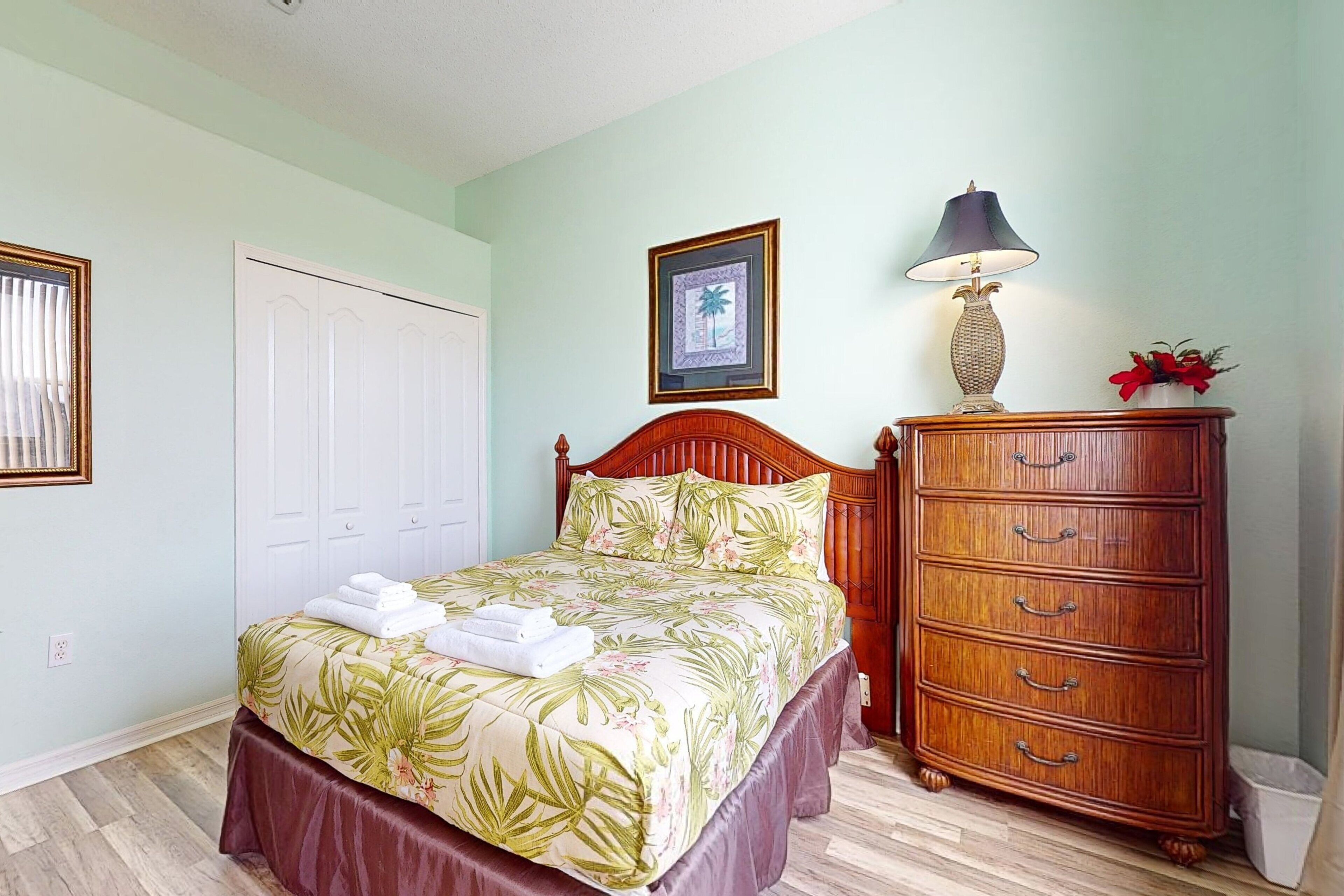 A bedroom with a bed, a dresser, a lamp, and a framed picture on the wall.
