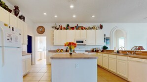 A modern kitchen with white cabinets, a central island, and a microwave. - Gated Community Home With Private Pool, Screened Lanai, & W/D - Near Disney/golf (Davenport)