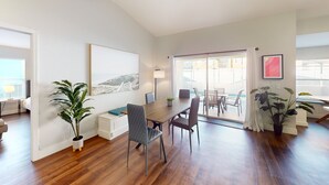 Une pièce spacieuse avec une table à manger en bois, des chaises, une grande fenêtre donnant sur un beau paysage et des plantes en pot.