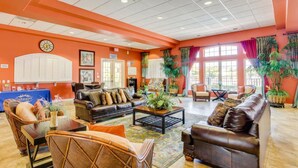 A spacious lobby with a large sofa, chairs, a coffee table, and potted plants. - Bright, Centrally-located Getaway With a Pool, Clubhouse, & Fast Wifi (Kissimmee)