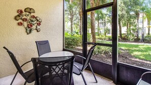 A room with a round table and chairs, a decorative wall piece, and a large window with a view of trees and a building. - Bright, Centrally-located Getaway With a Pool, Clubhouse, & Fast Wifi (Kissimmee)