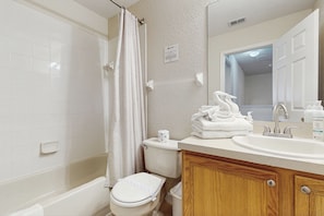 A bathroom with a bathtub, toilet, sink, and mirror. - Wonderful, Two-level Home Close to Theme Parks With W/d, Central AC & Patio (Davenport)