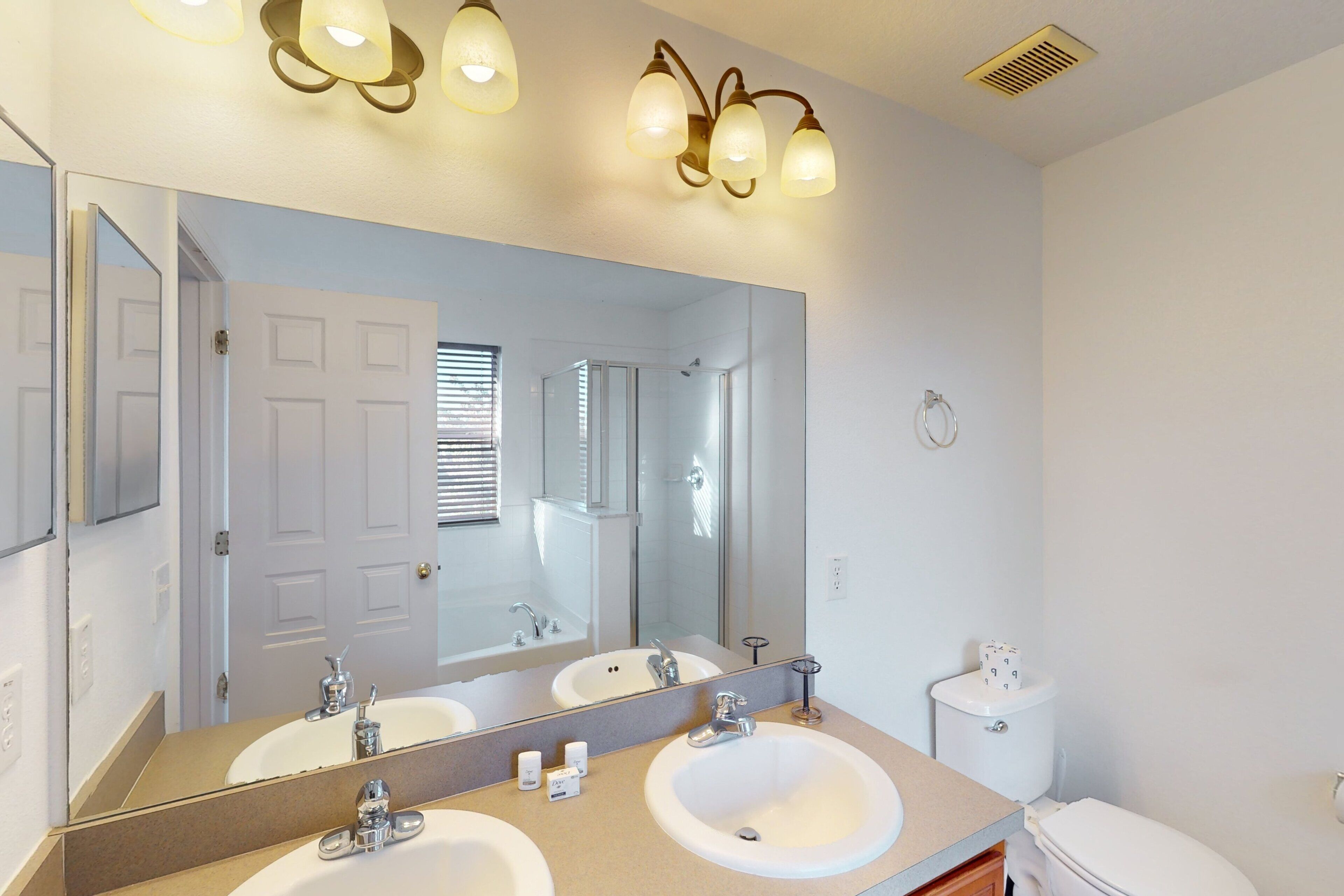 A bathroom with two sinks, a large mirror, and a toilet.
