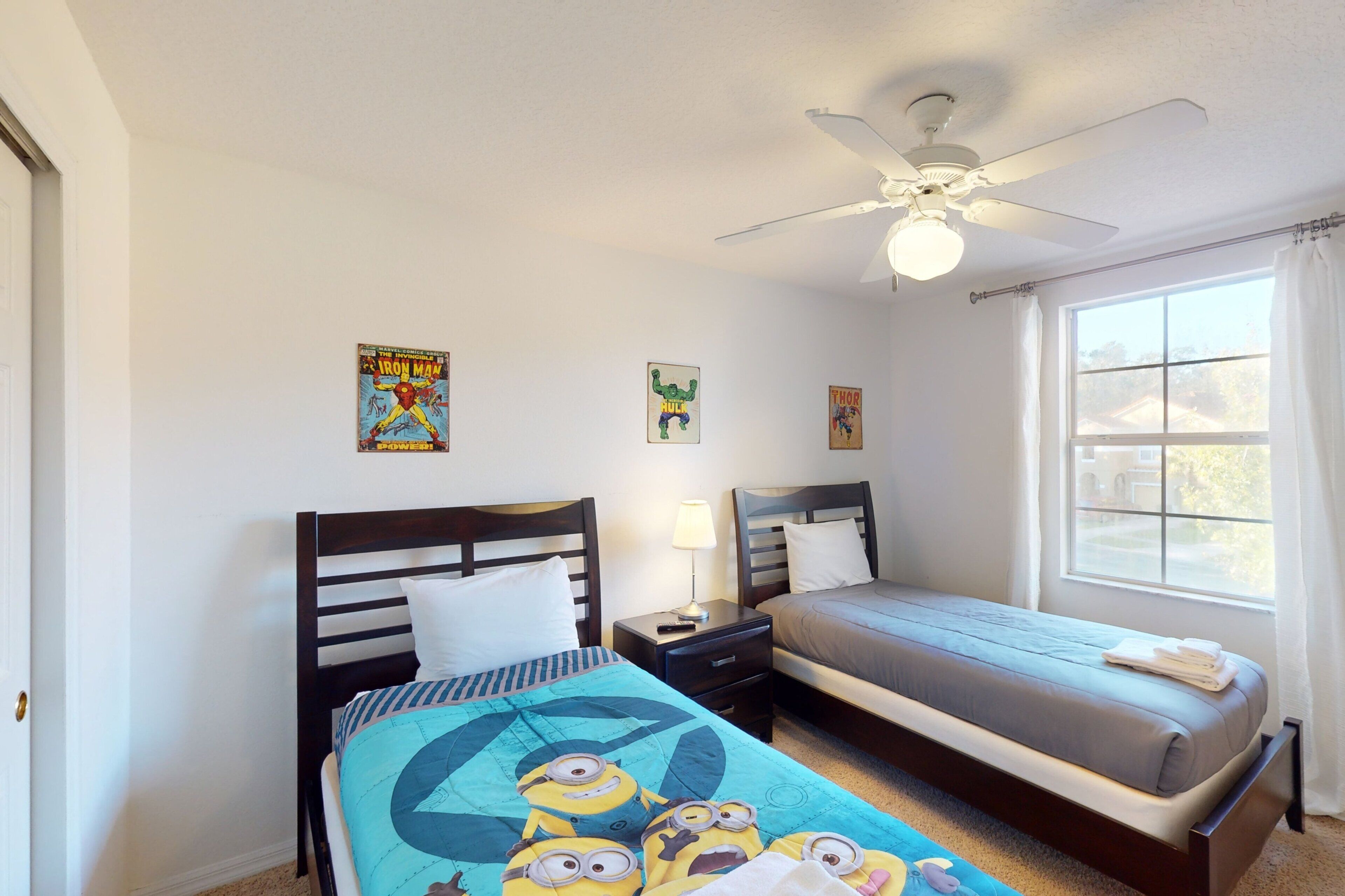A bedroom with two beds, a ceiling fan, and posters on the walls.