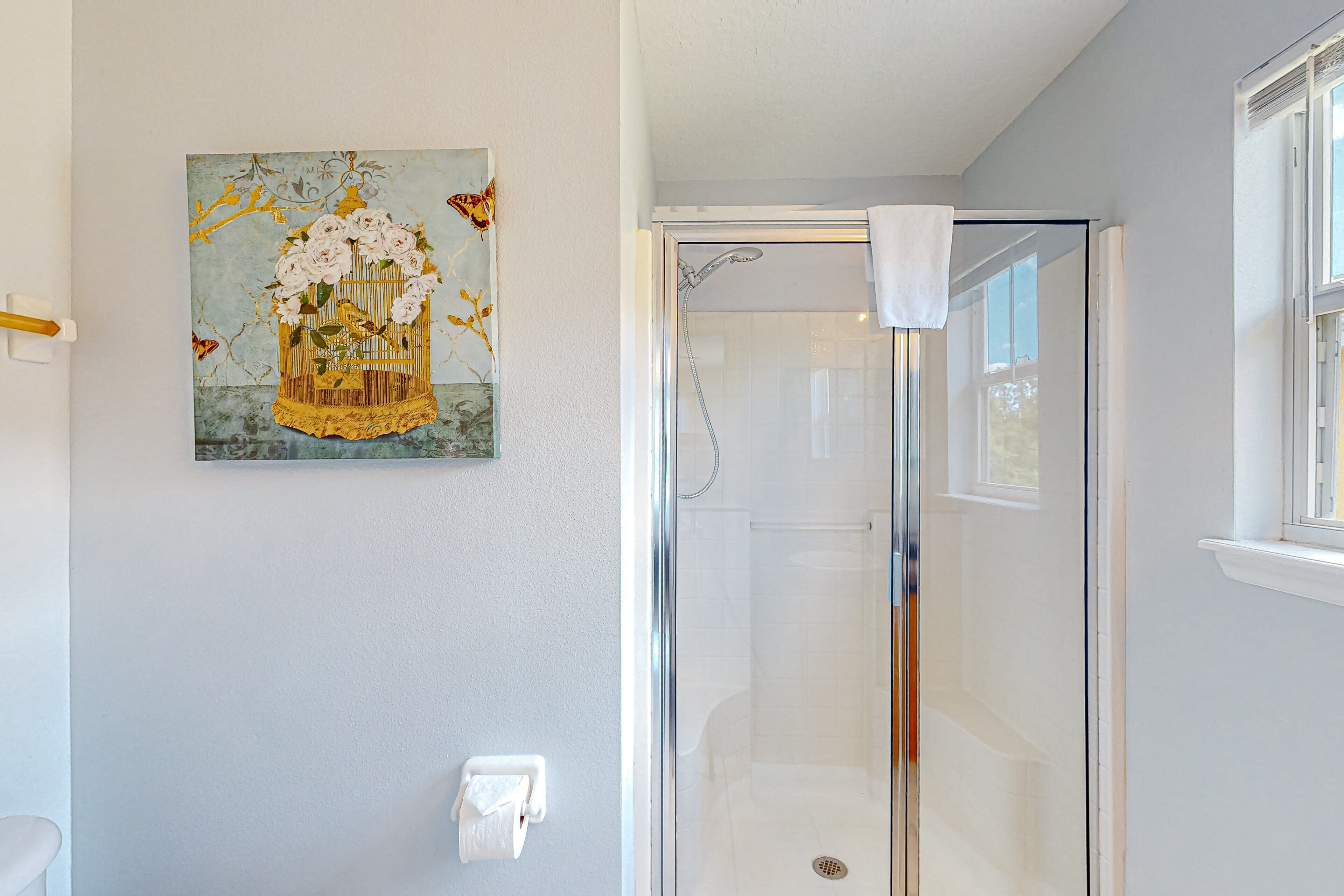 Une salle de bain avec une douche à parois de verre, des toilettes et un tableau accroché au mur.