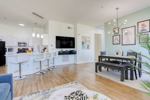 A modern kitchen with white cabinets, a microwave, and a large flat-screen TV. - Snowbird-friendly Condo Near Walt Disney World Resort W/pool, Wifi, AC, and W/D (Davenport)