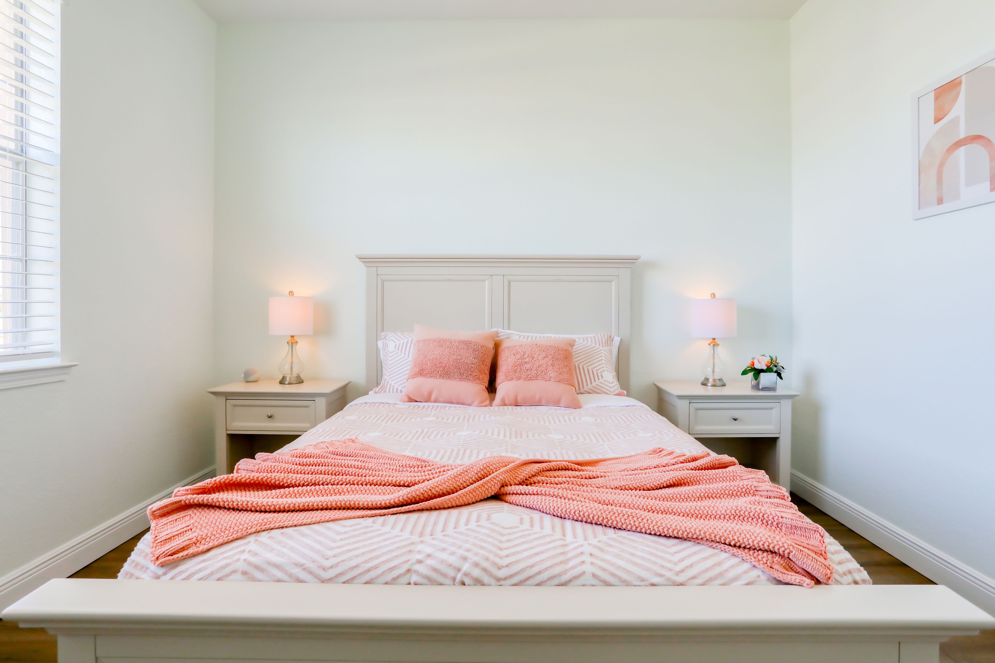 A neatly arranged bedroom with a bed, two bedside tables, and a window.