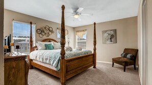 Ein Schlafzimmer mit einem Himmelbett, einem Deckenventilator, einem Sessel und Blick ins Freie.