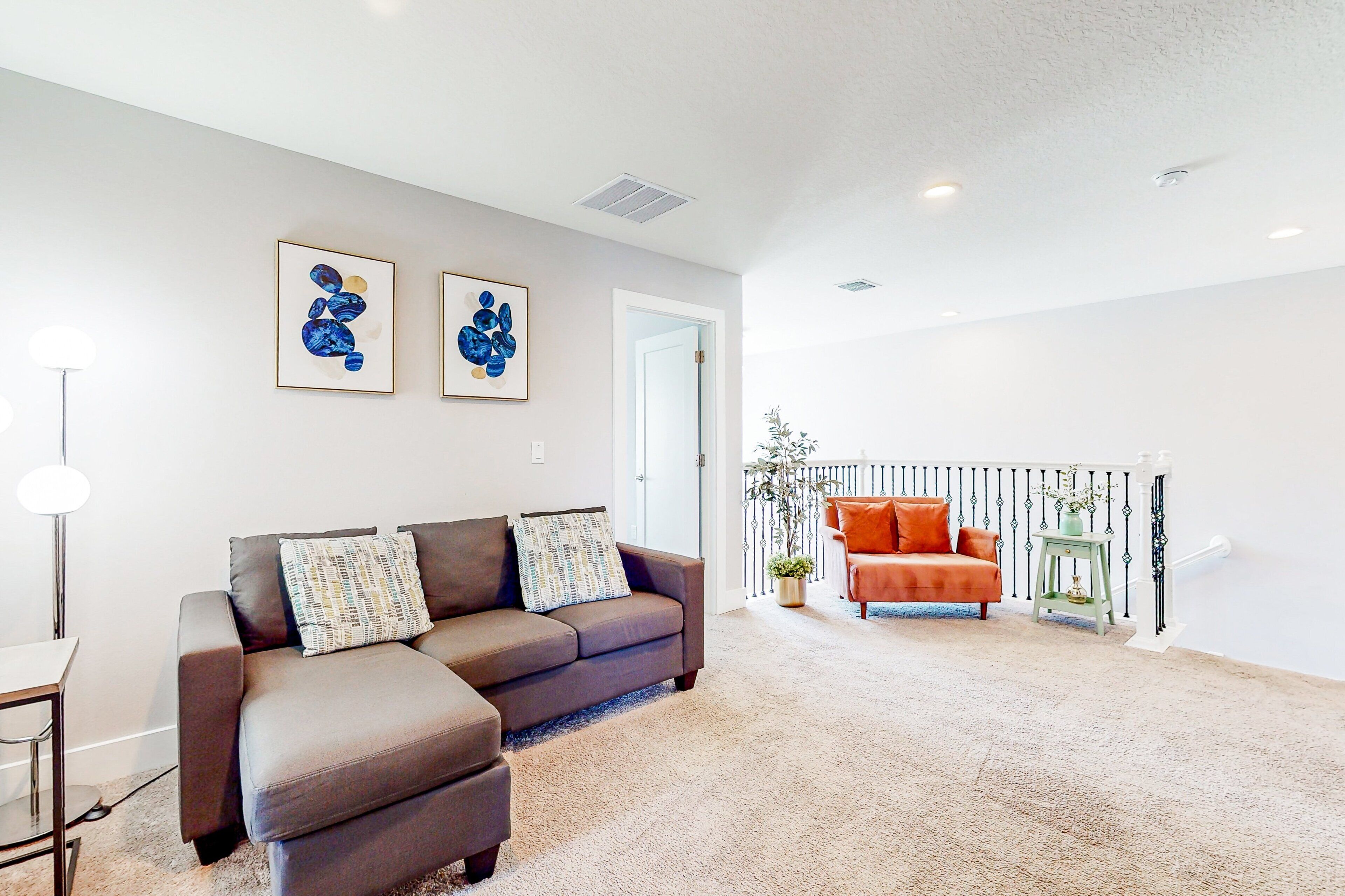 A living room with a sofa, a chair, and a small table. There are two framed artworks on the wall.