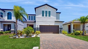 A two-story house with a garage, a driveway, and a well-maintained lawn. - Bright Home With Private Pool, Washer/dryer and Internet (Kissimmee)