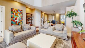 A spacious living room with a neutral color palette, featuring a large sectional sofa, a coffee table, and a colorful abstract painting on the wall. - Beautiful Home With Resort Pool and Space for the Whole Family (Kissimmee)