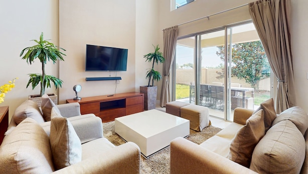 A spacious living room with a flat-screen TV, comfortable seating, and a large sliding glass door leading to an outdoor area. - Beautiful Home With Resort Pool and Space for the Whole Family (Kissimmee)