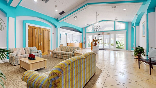 A spacious lobby with a high ceiling, a reception desk, and multiple seating areas. - Comfortable Townhome Near Disney With Athletic Courts & Pool Access, Patio, & AC (Davenport)