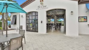 An outdoor seating area with tables and chairs, a bar & lounge entrance, and a clear view into the interior. - Beautiful Home With Private Pool and Space for the Whole Family (Kissimmee)