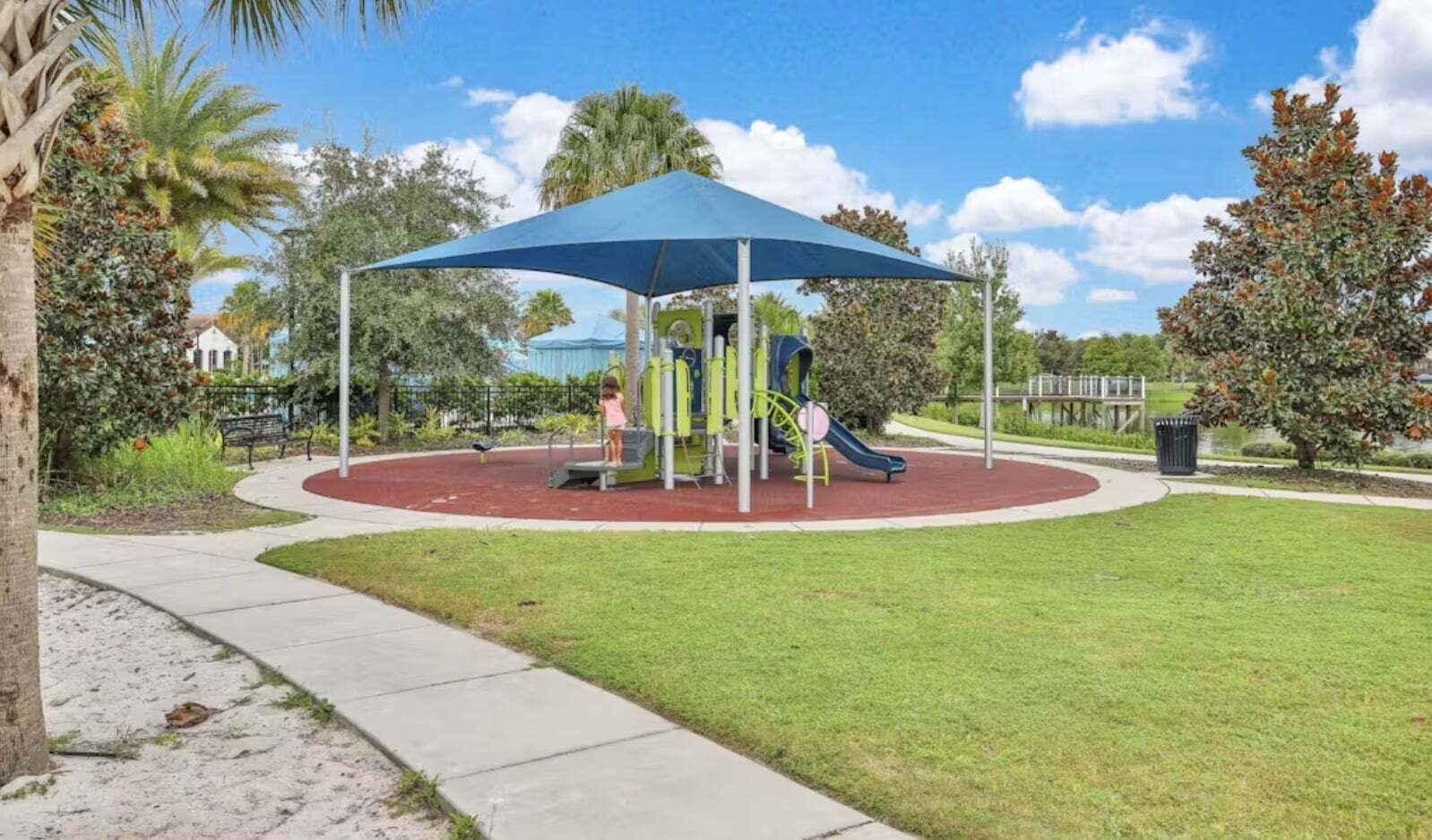 A playground with a blue canopy, a slide, and a climbing structure.