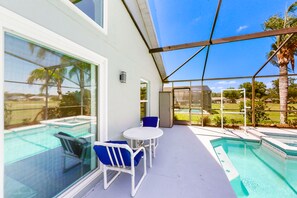 Ein überdachter Außenbereich mit Pool, Sitzgelegenheiten und Blick auf die umliegende Landschaft.