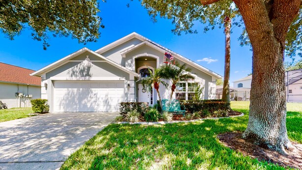 A residential house with a garage, a driveway, and a well-maintained lawn. - Private Pool Home With Spa, Screened Patio, Central AC, & Washer/dryer (Davenport)
