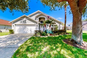 A residential house with a garage, a driveway, and a well-maintained lawn. - Private Pool Home With Spa, Screened Patio, Central AC, & Washer/dryer (Davenport)