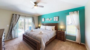 A bedroom with a bed, nightstands, a ceiling fan, a window with curtains, and a view of the outdoors. - Private Pool Home With Spa, Screened Patio, Central AC, & Washer/dryer (Davenport)
