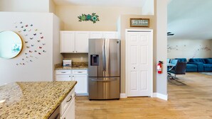 A kitchen with a stainless steel refrigerator, white cabinets, a granite countertop, and a sign that says 'this kitchen.' - Private Pool Home With Spa, Screened Patio, Central AC, & Washer/dryer (Davenport)