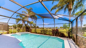 A clear swimming pool with a glass enclosure, surrounded by palm trees and a view of a golf course. - Private Pool Home With Spa, Screened Patio, Central AC, & Washer/dryer (Davenport)