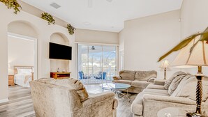 A living room with a sofa set, a coffee table, and a TV mounted on the wall. - Vibrant Modern Home With Private Pool, Spa, Lanai & Expansive Game Room (Haines City)
