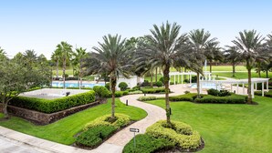 A landscaped garden with palm trees, a winding pathway, and a pool area. - Spacious and Inviting Getaway Condo Close to Disney and Universal (Kissimmee)